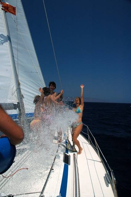 Girls in bikinis splashed with water on a sailboat deck
