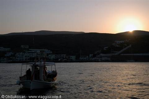 Fishing boat off a Greek island harbour at dusk, hills silhouetted behind