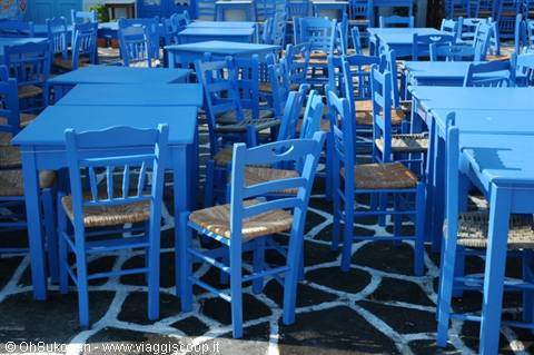 Blue wooden tables and straw-seated chairs on white painted ground
