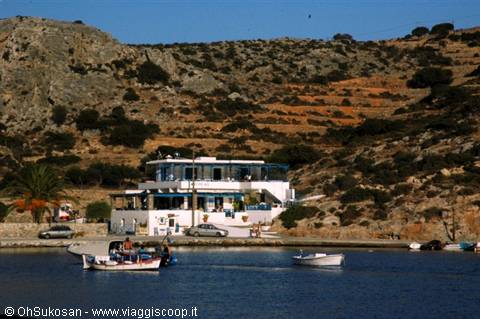 Fishing boats moored in front of a white seaside taverna