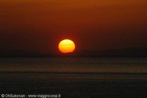 Red sun sinking into the sea before dark hills of Škrapa