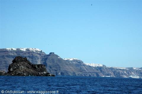 Volcanic cliffs topped by whitewashed houses, blue sea below, Santorini