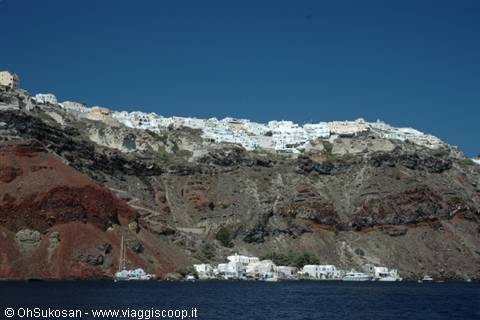 White houses on the cliff, small boats and harbor on blue sea, Santorini