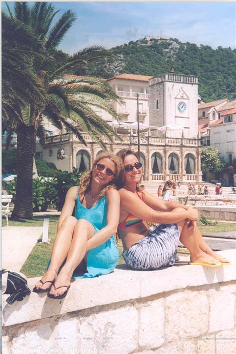 Two friends sunbathing on a stone wall along Hvar's waterfront