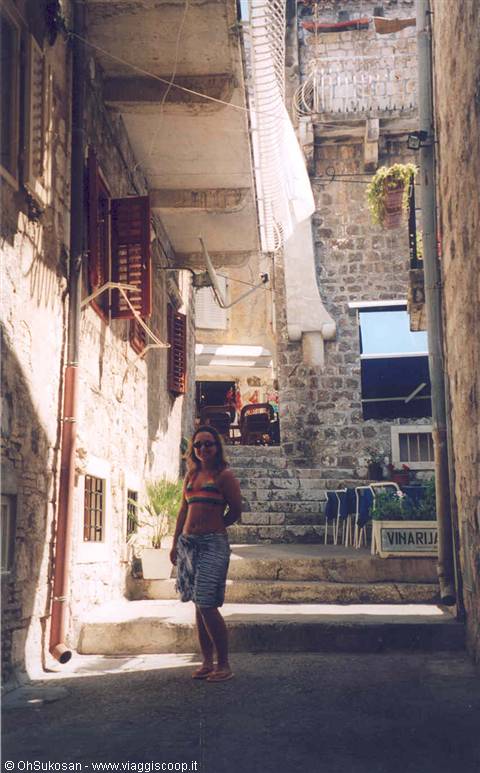 Woman in bikini by stone steps and Vinarija sign in alley