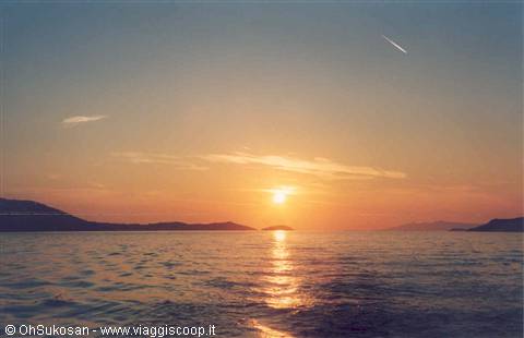 Low sun reflecting on calm sea among small dark islands