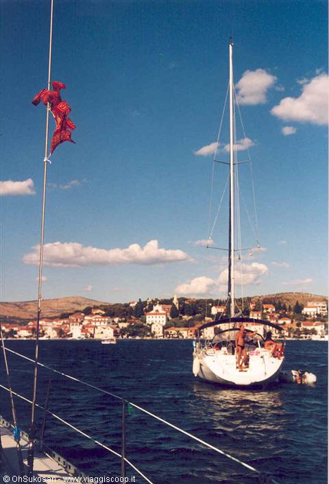 Sailboat anchored off Rogoznica village, blue sky with scattered clouds