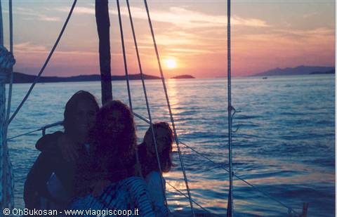 Girls on a sailboat deck as the sun sinks over the sea