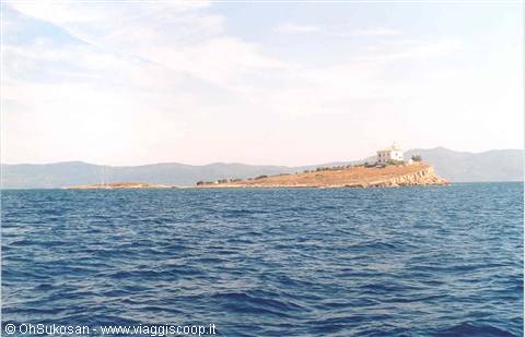 Arid islet with white building and lighthouse amid blue sea