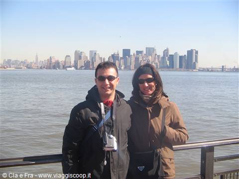 Couple with camera in front of Manhattan skyline, sunshine on the water