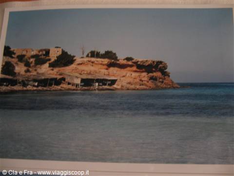 Fishermen's boathouses on reddish rocks and turquoise sea, Es Caló, Formentera