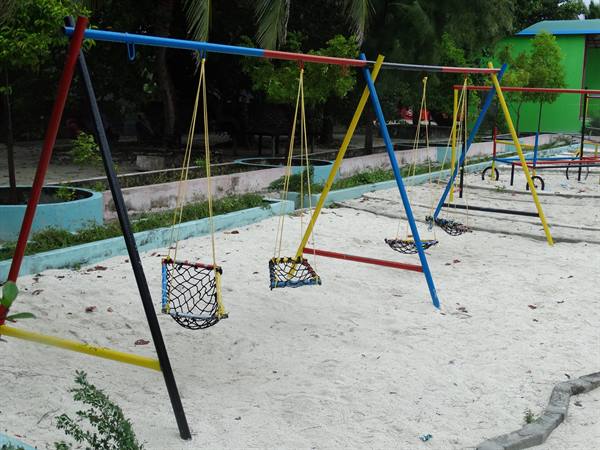 Colorful swings on white sand in a tropical playground