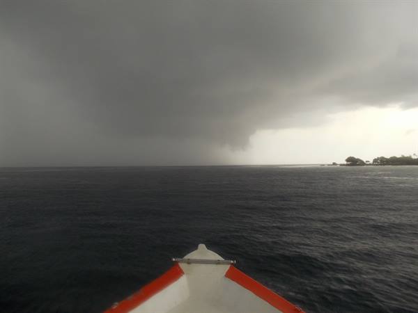 White and red boat bow on dark sea under storm cloud