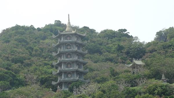 stone multi-tiered pagoda rising among green trees on the hill, Danang