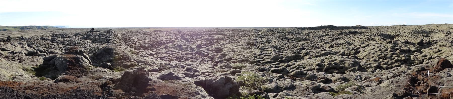 Campo di lava nera frastagliata sotto cielo chiaro, terra vulcanica desolata