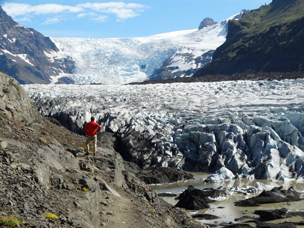 Hiker in red jacket in front of Svínafellsjökull glacier tongue