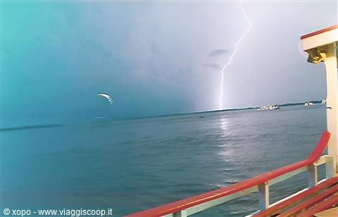 Lightning striking the sea beside a boat's red railing
