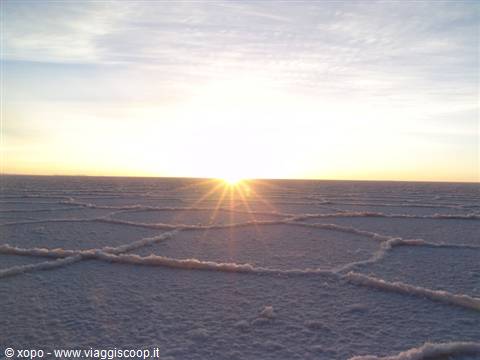 Salar de Uyuni: hexagonal salt crust at sunrise, sun rising on the horizon