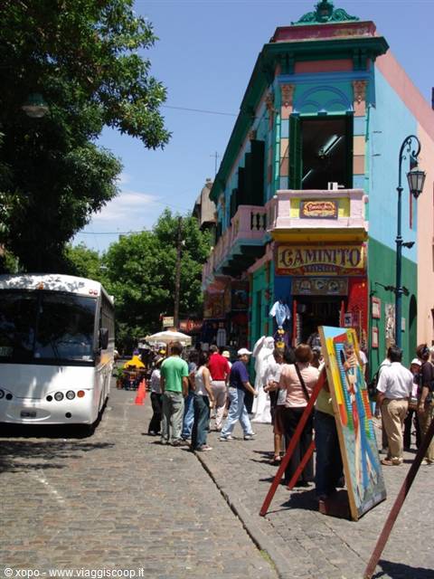 Tourists on cobblestones in front of Caminito's colorful painted house