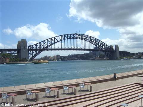 Sydney Harbour Bridge seen from Opera House steps, empty tables under cloudy sky