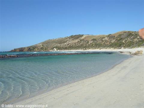 White sand beach with turquoise water and dry hills in the background