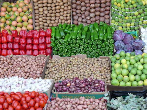 Market stalls with peppers, potatoes, garlic, tomatoes and limes arranged in boxes