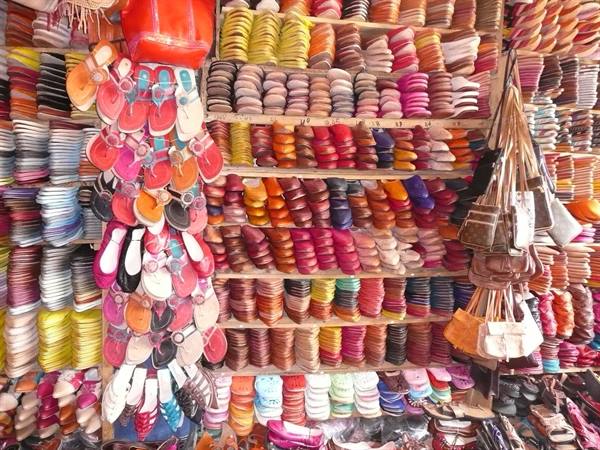 Souk stall stacked with colorful leather babouche slippers and hanging bags