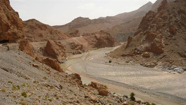 Green river winding between red rocks and carved mountain roads