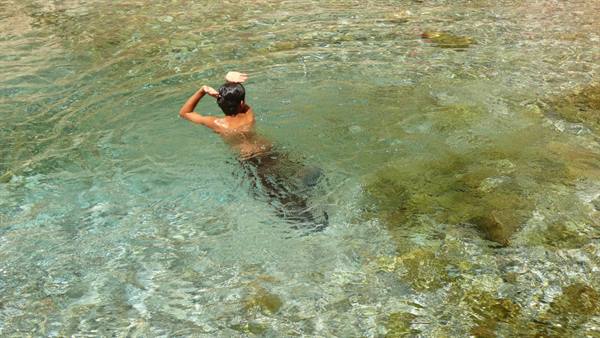Man swimming in clear turquoise water over green rocky seabed