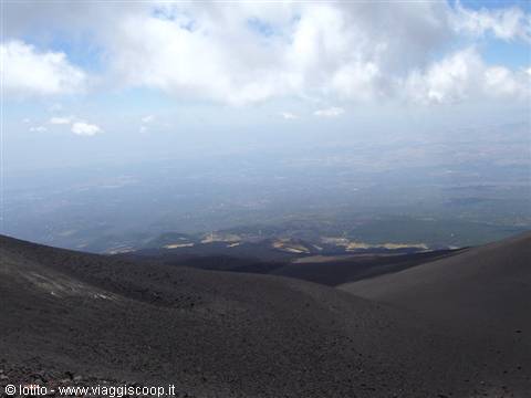 Vesuvius: dark volcanic sand craters over hazy city beneath clouds