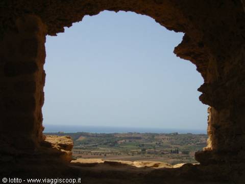 Ancient stone arch framing the sea and farmland, Agrigento