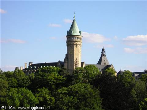 Stone tower with green spire of Luxembourg bank above the trees
