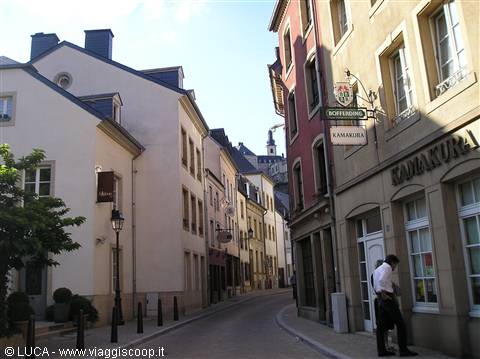 Man at a shop door on a cobblestone street in Luxembourg