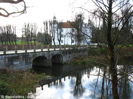 Stone bridge with three arches in front of a white villa, bare trees