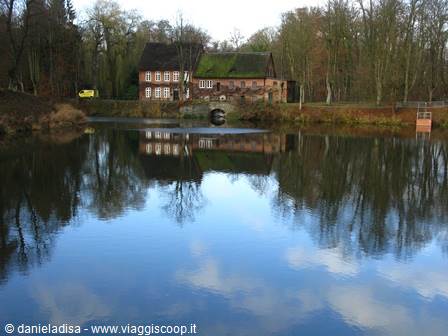 Brick mill with thatched roof reflected in the lake