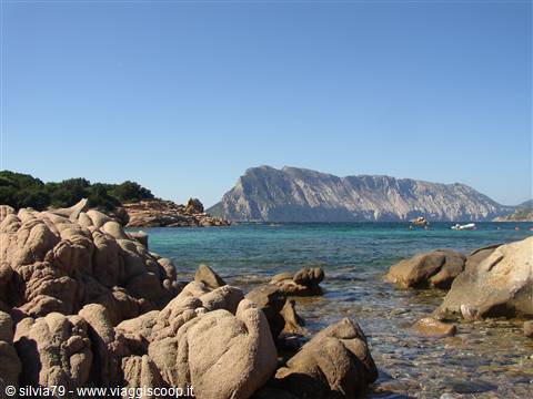 Pink granite rocks and turquoise water in front of Tavolara island, clear sky