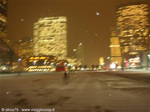 Snowy night in La Défense, blurred skyscrapers and pedestrians under glowing lights