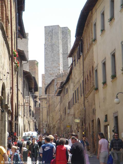Tourists crowd a medieval street in San Gimignano among stone towers