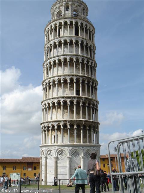Tourists beneath the Leaning Tower of Pisa, white marble loggias, cloudy sky