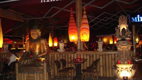 Golden Buddha statue and glowing lanterns inside Miró bar with bamboo decor