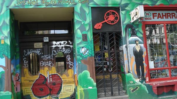 Green mural-painted facade with graffiti entrances and a bicycle shop sign
