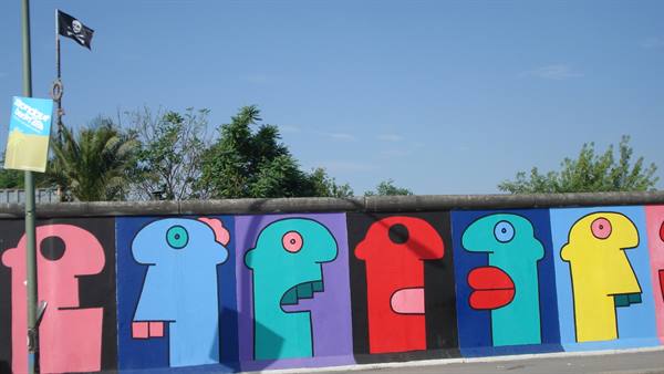 Colorful painted faces on the Berlin Wall at East Side Gallery, blue sky