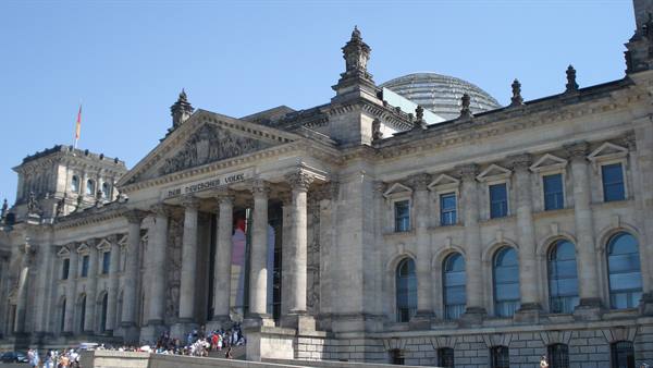 Tourists on the steps in front of Berlin's Reichstag, stone columns and glass dome