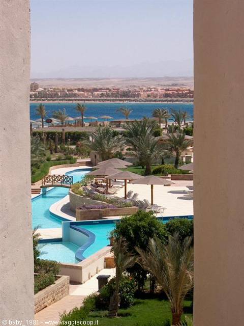 Pool with parasols and palm trees framed by columns, Red Sea behind