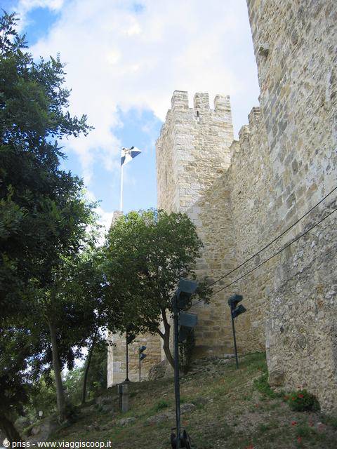 Crenellated walls of São Jorge Castle in Lisbon with waving flag