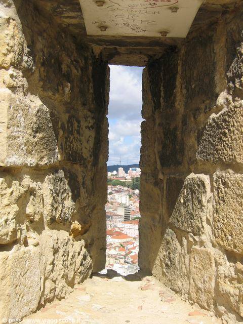 Arrow slit in stone tower of São Jorge Castle, Lisbon rooftops below
