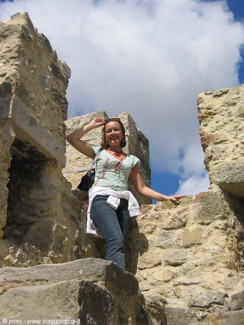 Smiling woman among limestone ruin walls under a cloudy sky