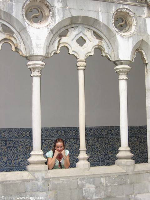 Woman leaning on marble columns of Pena cloister, blue azulejo tiles