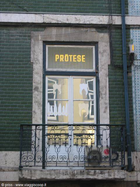 Yellow "Prótese" sign above a door with painted dentures, green tiled facade