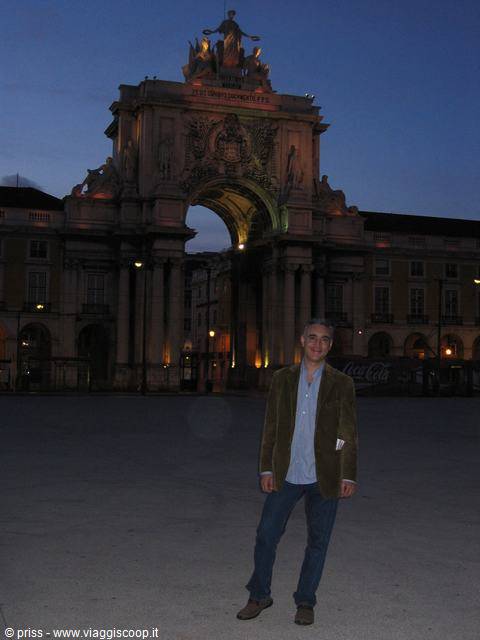 Traveler in corduroy jacket in front of Rua Augusta Arch, Lisbon, evening